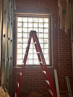 red ladder next to window with glass blocks